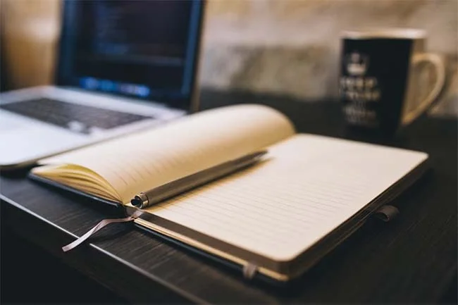 Photo libre de droit avec un calepin ouvert à coté d'un pc illustrant la thématique de l'article : Blog d'entreprise en Algérie